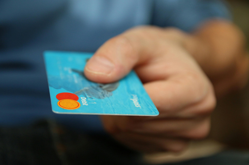 Close-up-of-a-hand-holding-a-blue-credit-card,-indicating-a-transaction-or-payment-process.